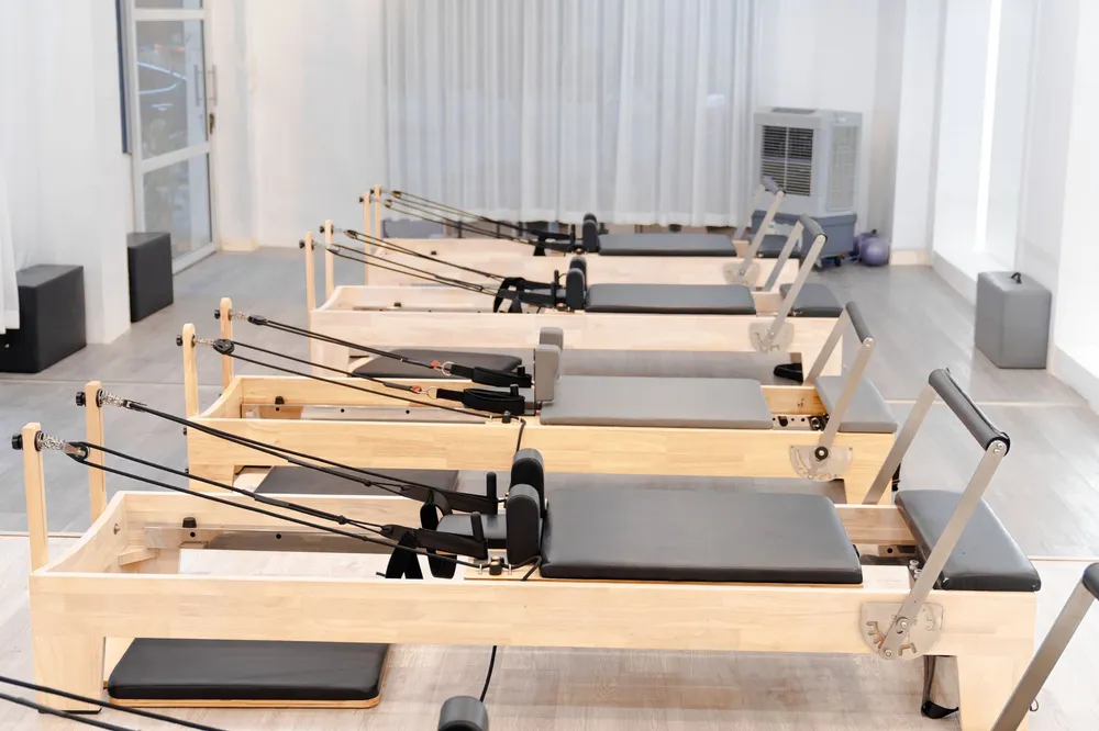 Sala de pilates máquinas con reformers de madera y luz natural
