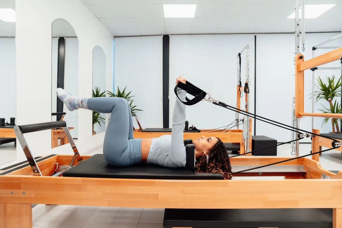Alumna en el reformer durante una clase de pilates máquinas
