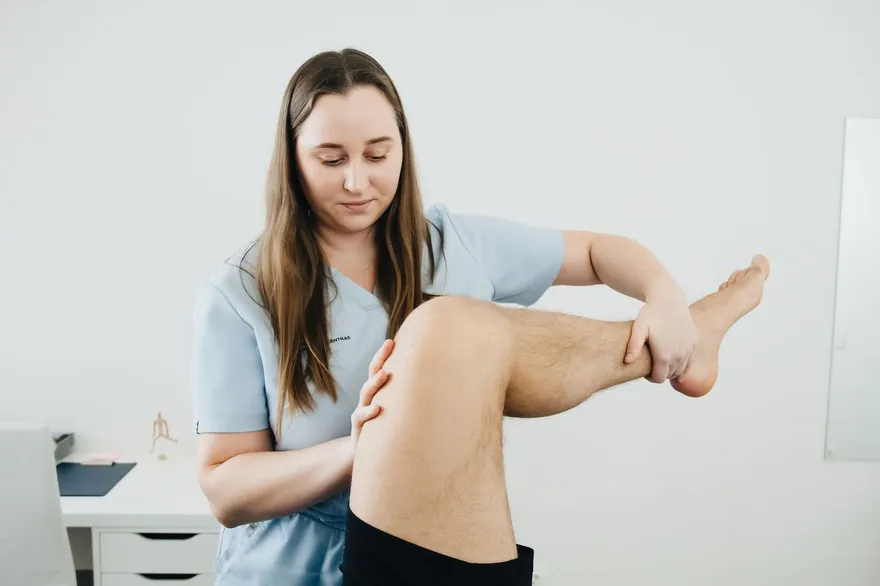 Fisioterapeuta guiando el ejercicio de rodilla de un paciente en rehabilitación